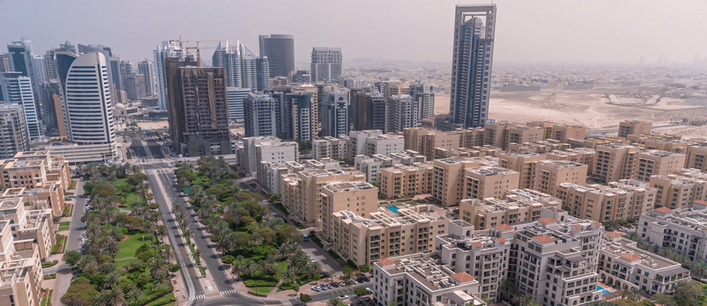 Aerial view of Al Barsha, palm-lined streets, and desert haze in a city skyline