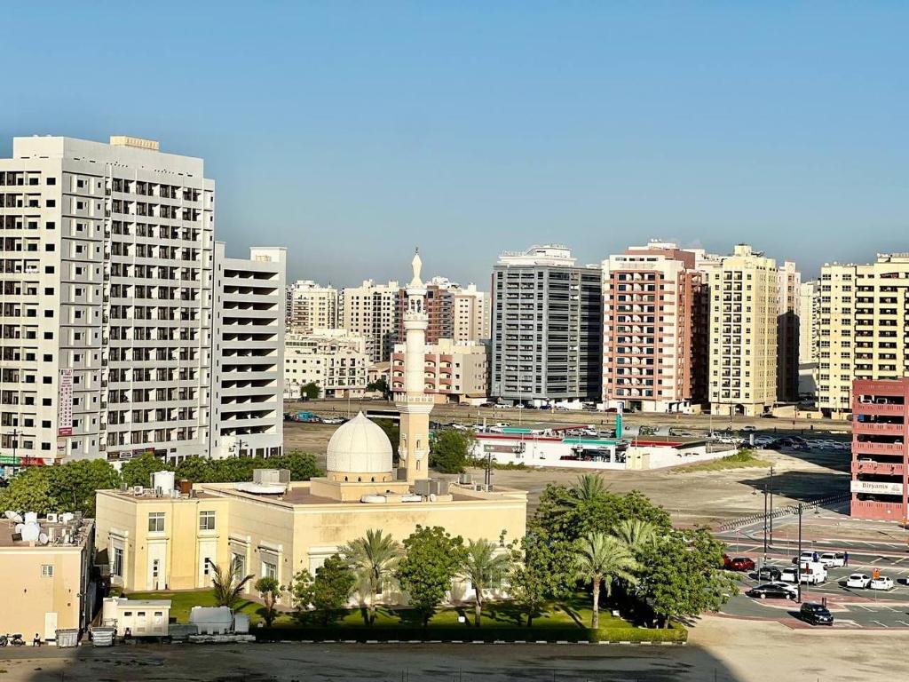 Al Nahda skyline with apartment towers and a mosque in the foreground under a clear blue sky