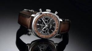Luxury Breitling chronograph wristwatch with brown leather strap on a reflective black surface