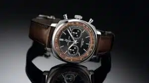 Luxury Breitling chronograph wristwatch with brown leather strap on a reflective black surface