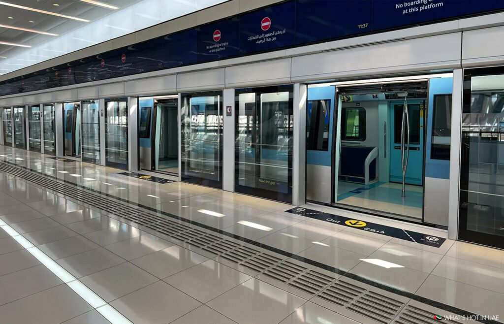 Empty metro platform with glass platform screen doors and an open train door on the right