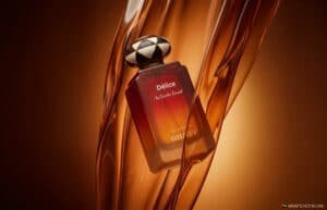 Perfume bottle labeled Délice by Quentin Roussel and GHAFF against flowing amber glass strands