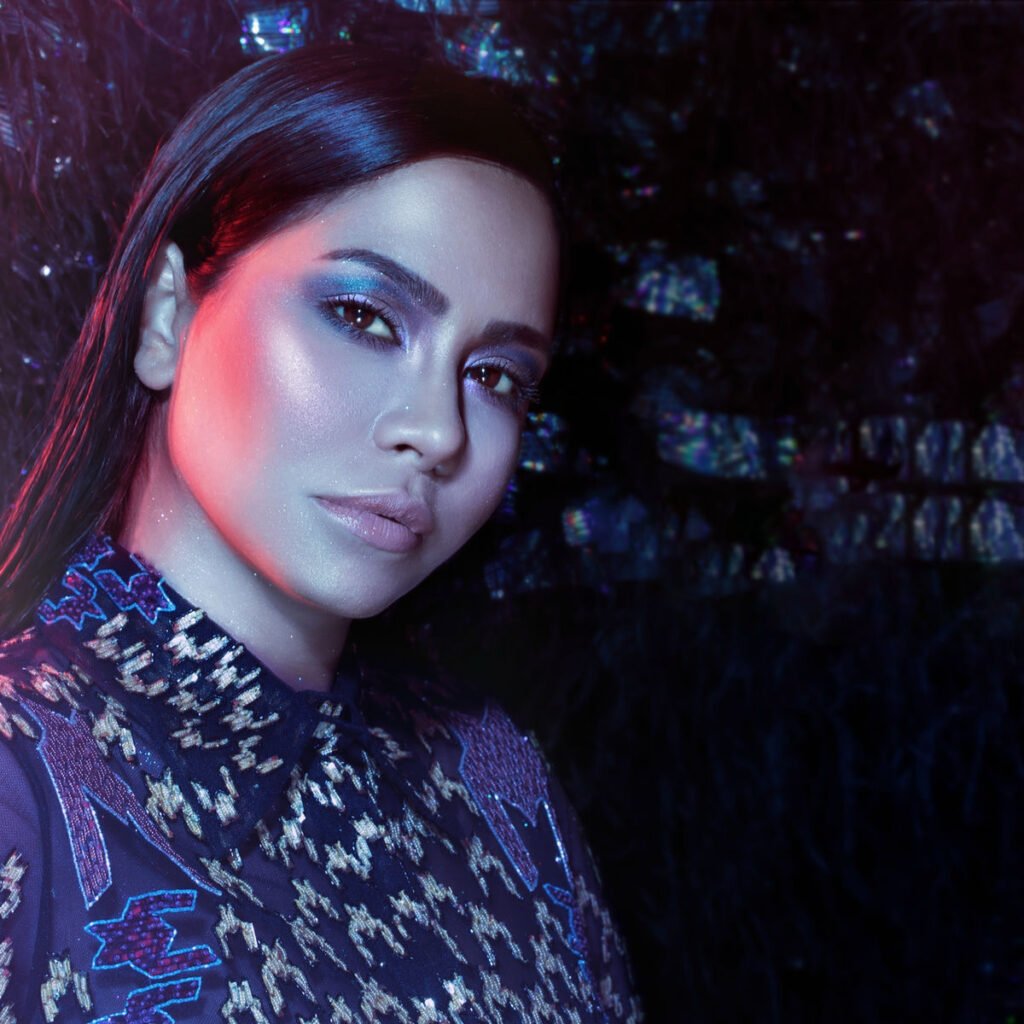 Close-up portrait of a woman with blue eyeshadow and sleek dark hair, lit by pink and blue neon light