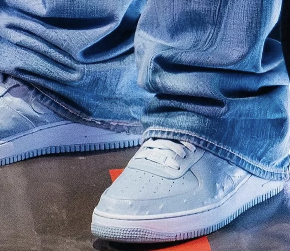 Close-up of Travis Scott x Nike Air Force 1 'Ice Blue Ostrich sneakers with jeans pooling over them on a dark floor