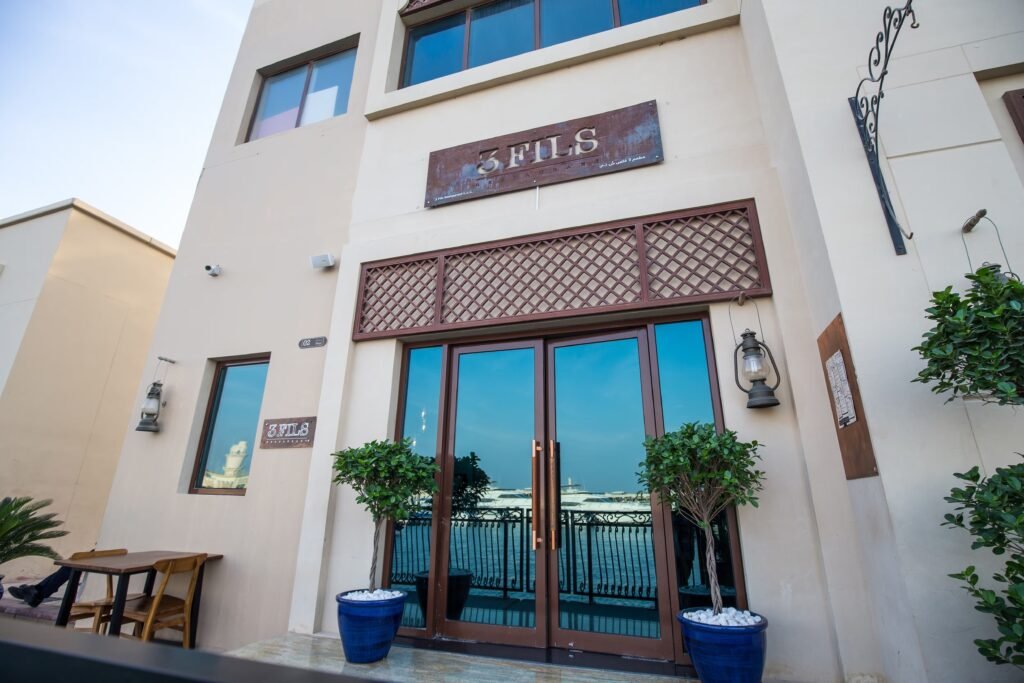 Entrance to 3 Fils restaurant with waterfront view and blue potted plants