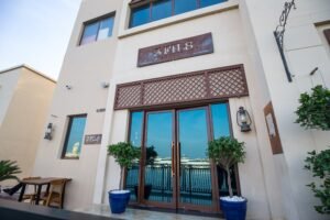 Entrance to 3 Fils restaurant with waterfront view and blue potted plants
