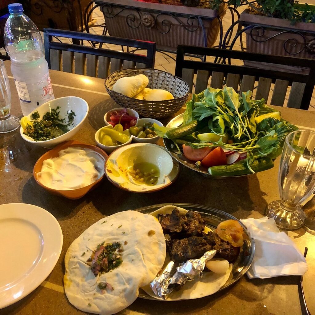 Table set with flatbread, grilled meat, fresh vegetables, dips, and bread baskets in a restaurant
