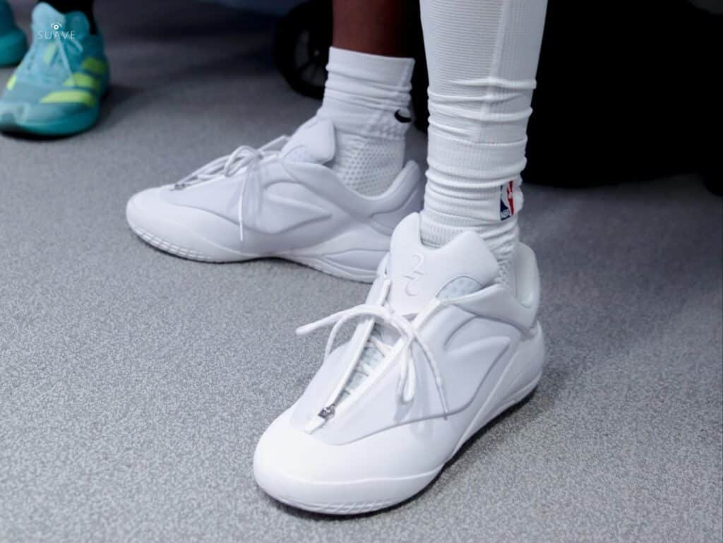White converse shai 001 ghosted sneakers worn with white socks on a gray floor
