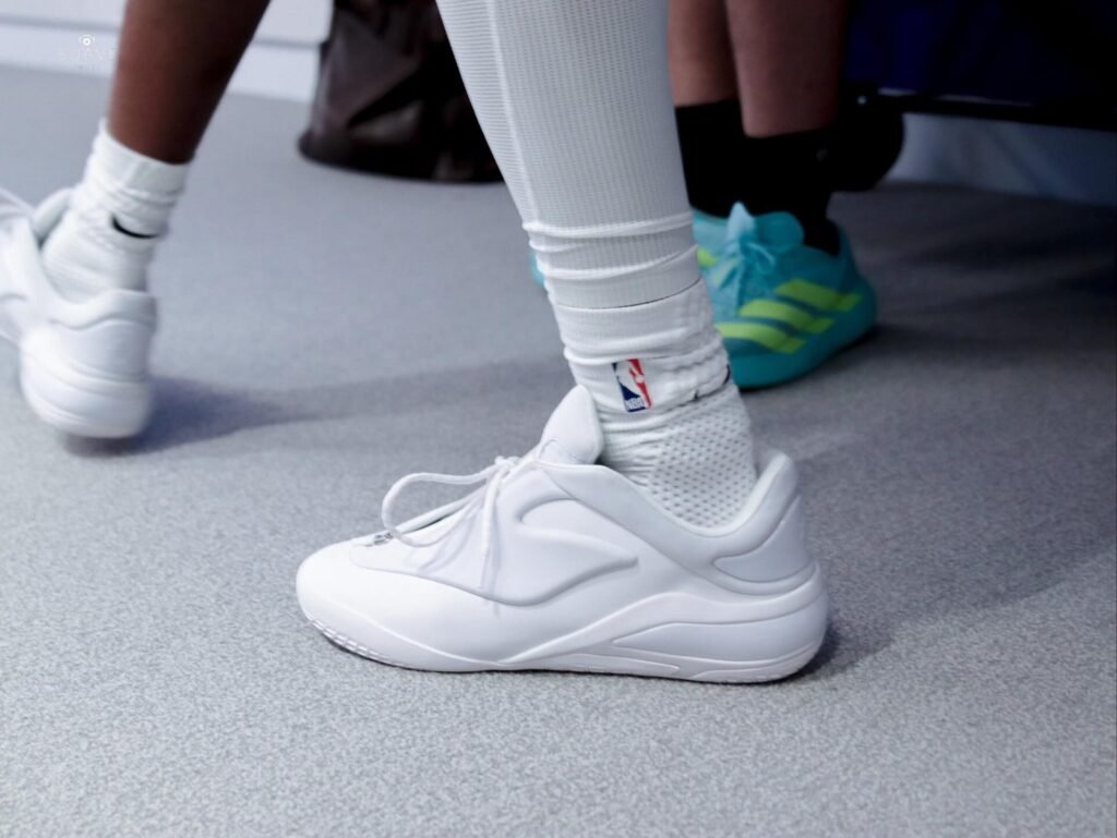 Close-up of a basketball player wearing white high-top sneakers and socks on a court