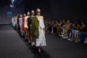 Models walk a runway in a fashion show as an audience watches from both sides