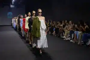 Models walk a runway in a fashion show as an audience watches from both sides