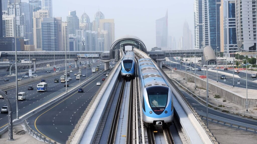 Two Dubai public transport blue metro trains on elevated tracks in a modern city skyline, with highways and high-rises in the background