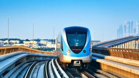 Modern blue subway train on elevated tracks with a city skyline in the background