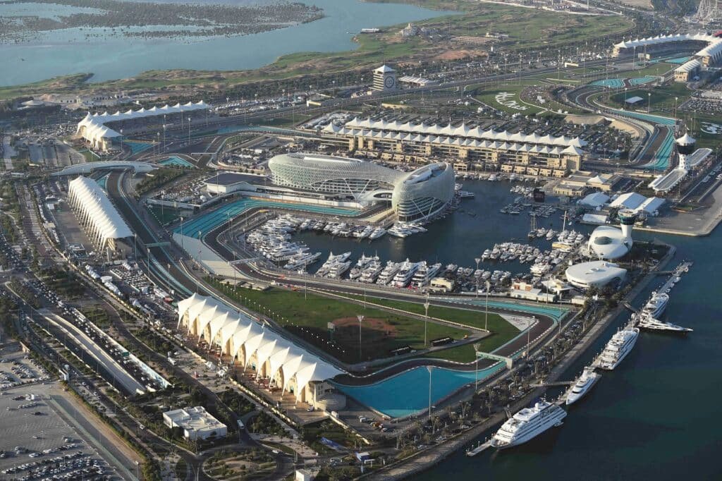 Aerial view of Abu Dhabi F 1 circuit with yachts, grandstands, and modern buildings beside the marina