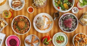 Overhead view of assorted colorful Middle Eastern dishes and drinks arranged on a wooden table