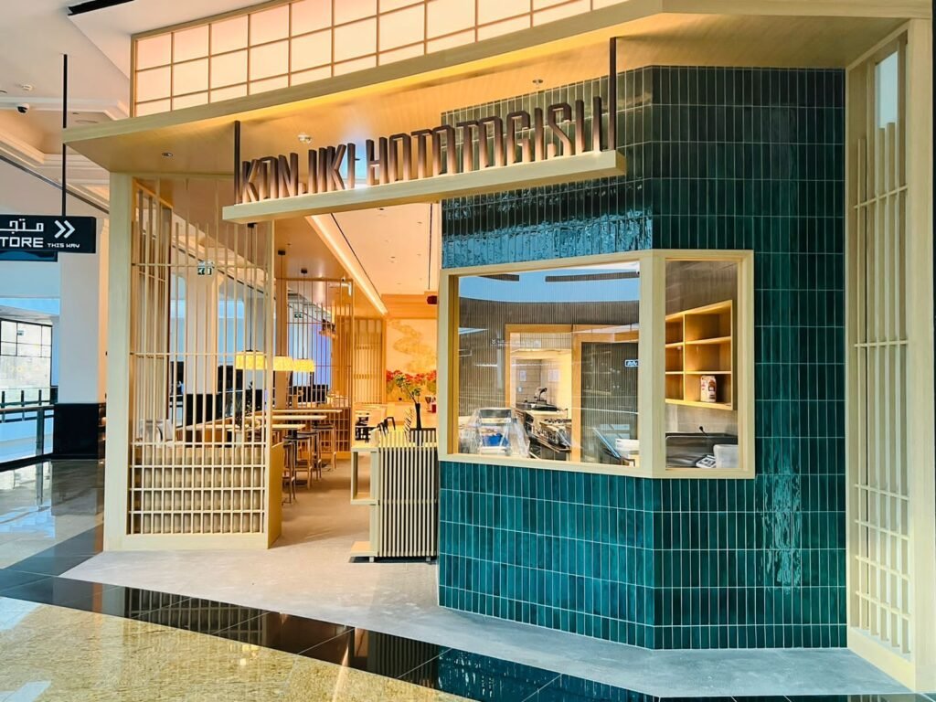 Modern Japanese restaurant storefront with teal tile walls and a visible kitchen counter inside