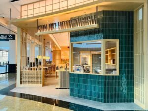 Modern Japanese restaurant storefront with teal tile walls and a visible kitchen counter inside