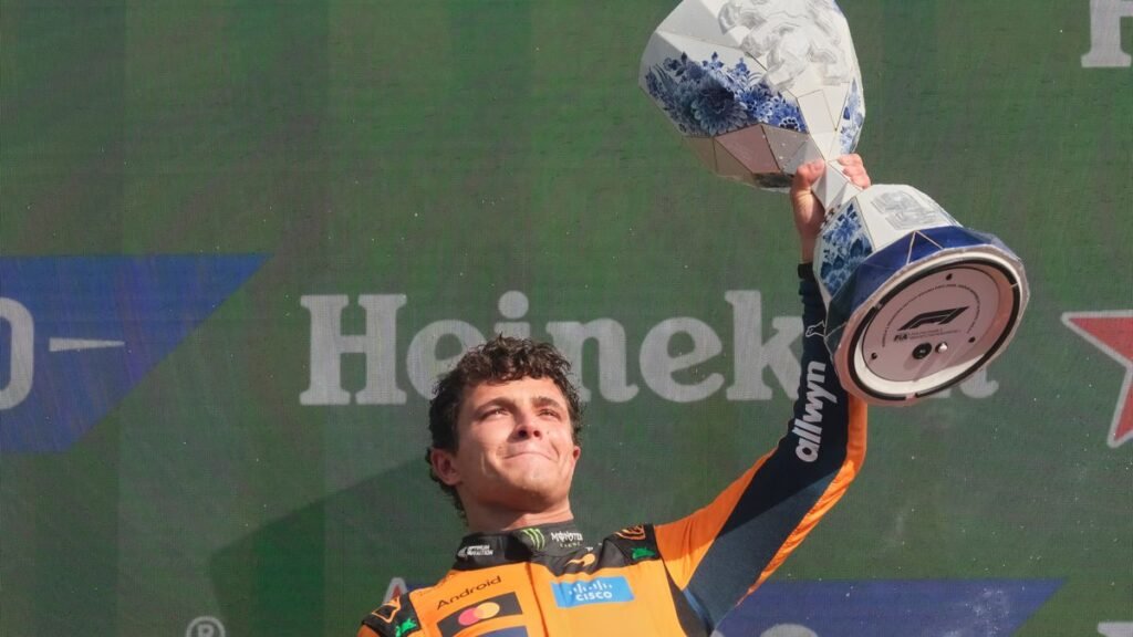 McLaren Formula 1 driver Lando Norris raises a trophy during a podium celebration