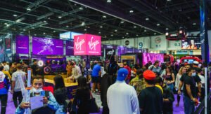 Crowded comic convention floor with colorful vendor booths, gaming displays, and a large Virgin Megastore sign overhead