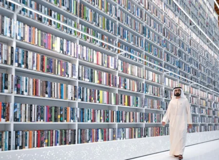 Man in traditional white robes walking beside towering bookshelves in a modern library