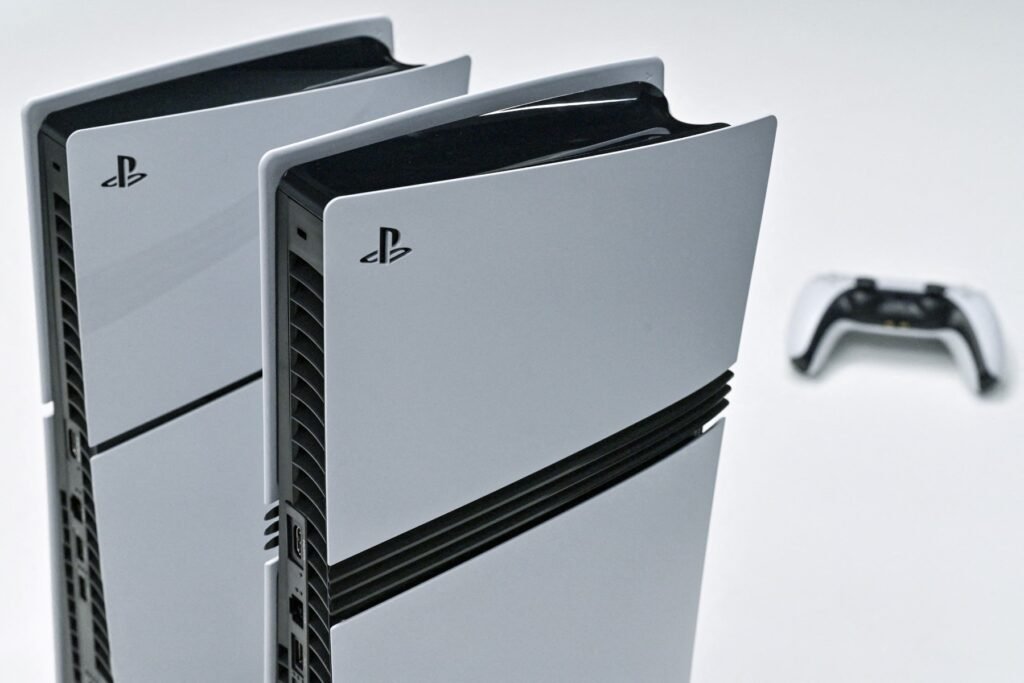 Two PlayStation 6 consoles standing side by side with a controller in the background