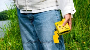 Person holding a yellow Pikachu-themed Polaroid camera in a grassy field