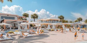 Modern beach resort with pool, lounge chairs, umbrellas, and people relaxing under palm trees