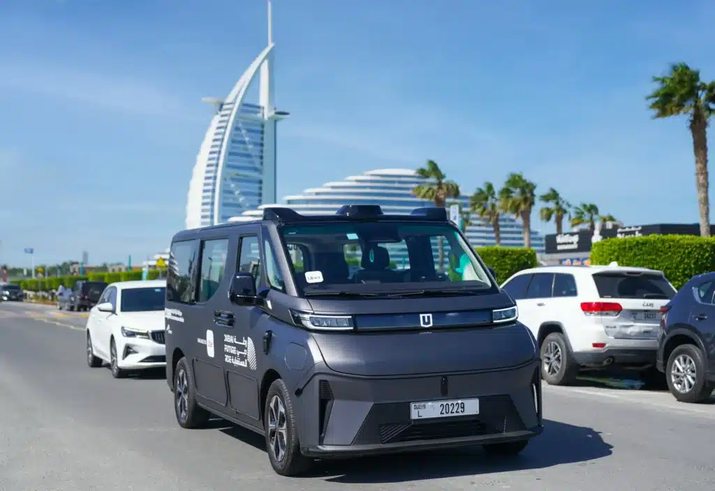 autonomous taxi with an Uber sticker parked in Dubai, with the Burj Al Arab and palm trees in the background