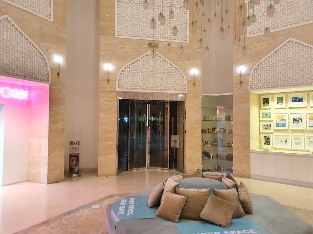 Dubai Ladies Club lobby with patterned arches, hanging lanterns, circular cushioned seating, and illuminated display shelves