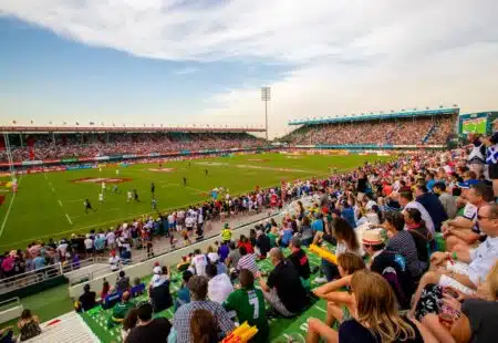 Crowded rugby stadium with players on the field and spectators filling the stands on a sunny day