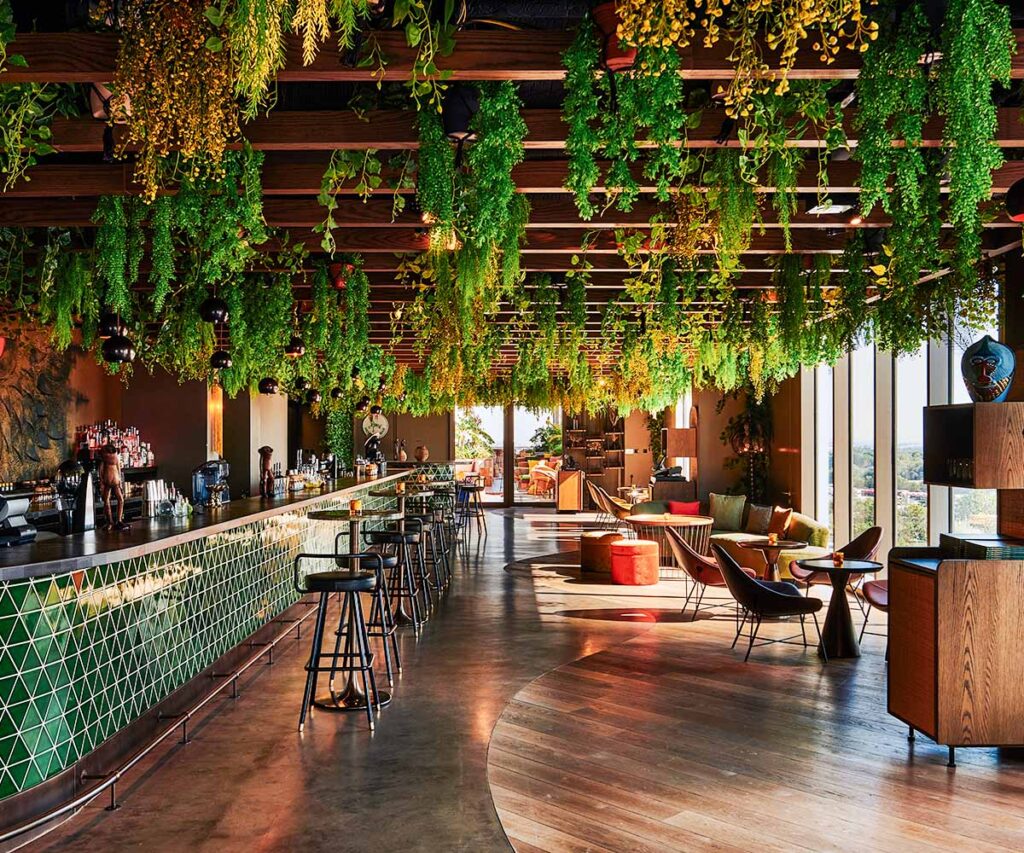 Monkey Bar Dubai lounge with a long tiled counter, modern seating, and abundant hanging greenery