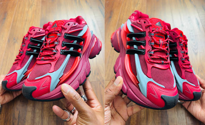 Pair of red and black Pharrell x adidas Adistar Jellyfish 'Red' athletic sneakers with light blue accents, shown from multiple angles over a wooden floor
