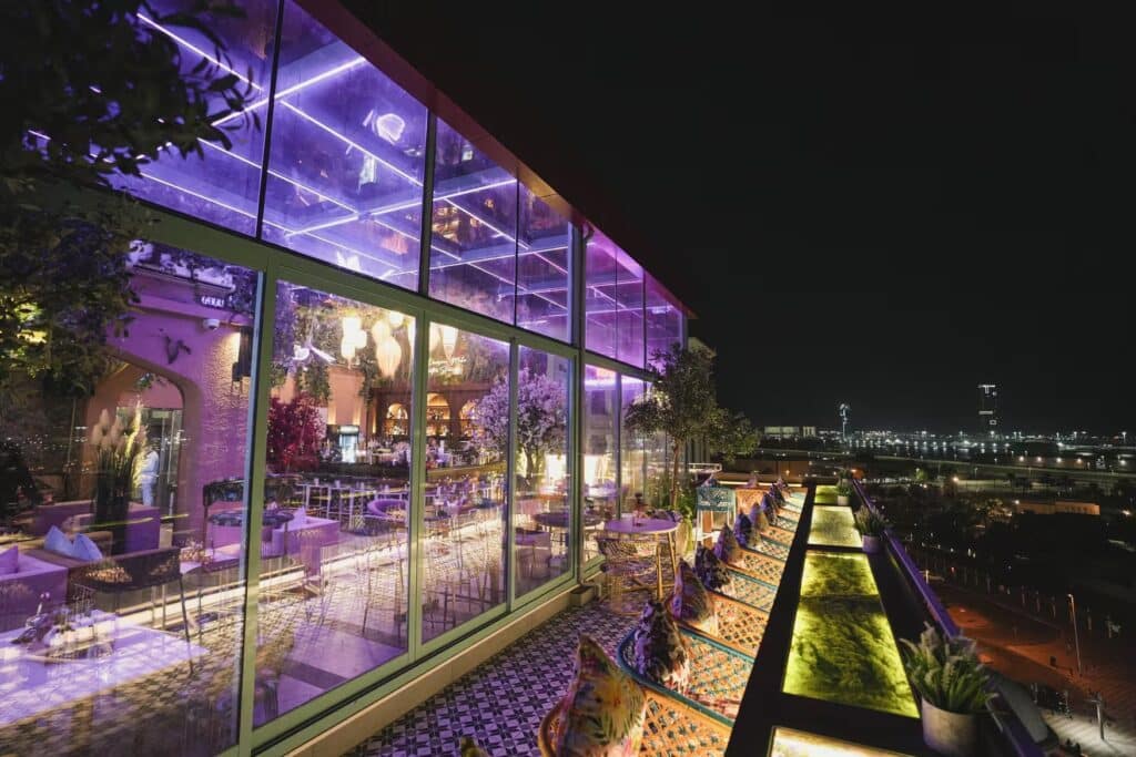 Purple-lit stories lounge dubai rooftop restaurant and bar with glass walls, patterned seating, and nighttime waterfront views