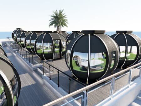 Futuristic spherical rooftop dining pods with glass windows, arranged along a deck overlooking the sea