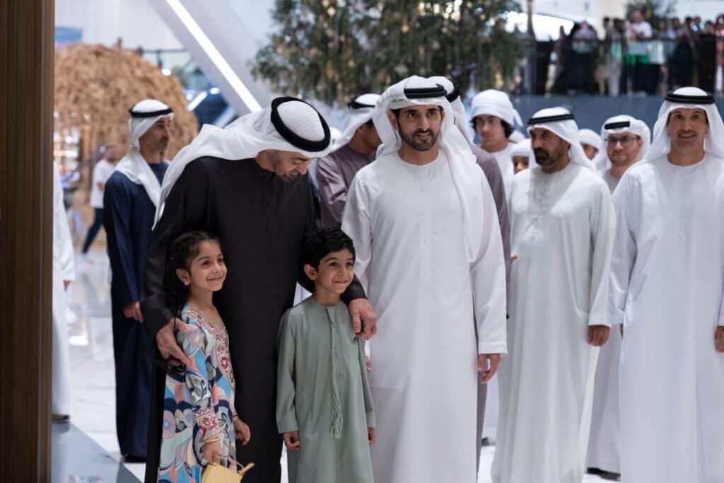 The President and Crown Prince and children gathered indoors, with a man in black embracing two children among men in traditional white attire for a UAE viral moment.