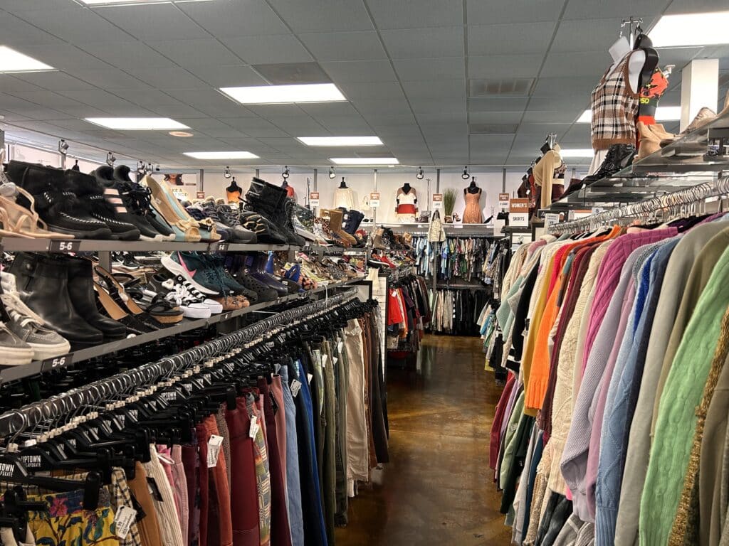 Thrift Clothing and shoe displays fill the aisles of a brightly lit thrift store