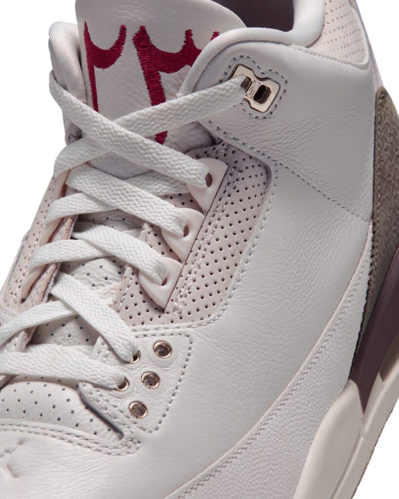 Close-up of an Air Jordan 3 sneaker with white laces, perforated panels, and red embroidered lettering