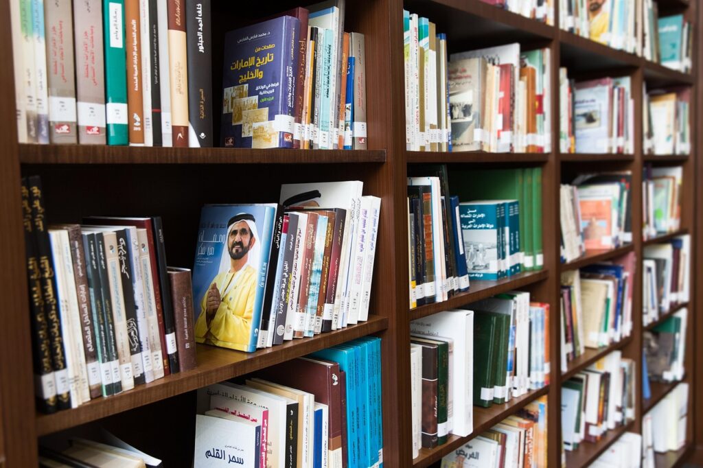 Bookshelves filled with Arabic-language Arab books, including a prominent book featuring a portrait of Sheikh Mohammed bin Rashid Al Maktoum