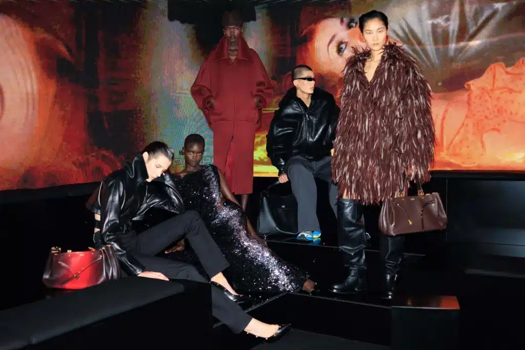 Five fashion models pose in Balenciaga Couture avant-garde outfits in front of a colorful digital backdrop