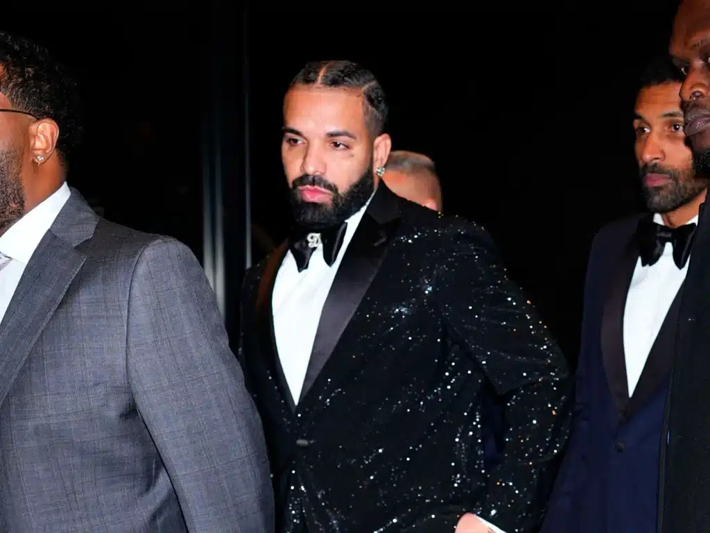 Drake in a sequined tuxedo poses with two men in formalwear at his 40th birthday party, where he received a Ferrari Testarossa as a gift.