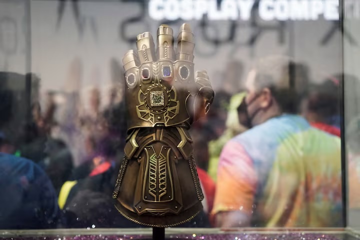 Ornate jeweled Infinity Gauntlet displayed in a glass case at a cosplay event