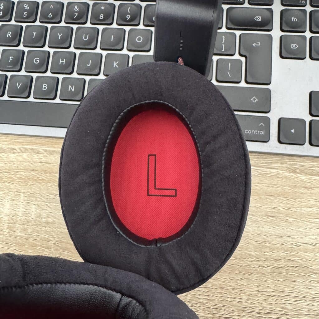 Close-up of the headset’s soft black ear pad, red inner lining and left-ear L marking.