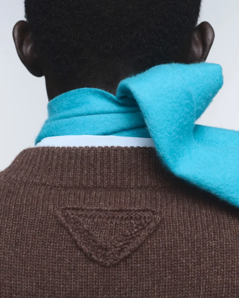 Person seen from behind wearing a bright turquoise scarf and brown knit sweater