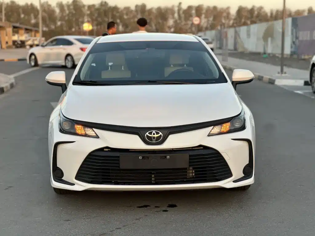 White Toyota sedan car in Dubai viewed from the front in a parking area