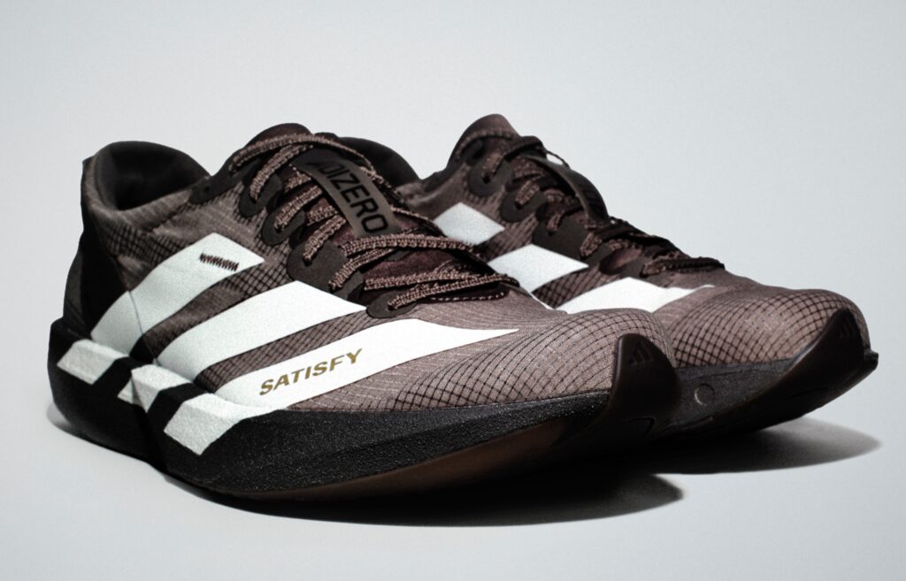 Pair of black-and-white athletic shoes labeled “ZERO” and “SATISFY.”