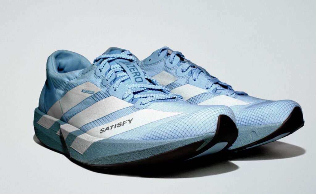 Pair of light blue adidas x SATISFY: The Second ADIZERO Capsule running shoes with “SATISFY” and “ADIZERO” branding