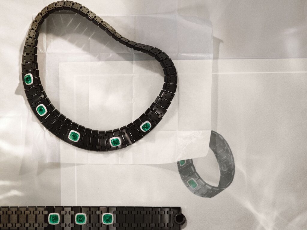 Black segmented Audemars Piguet Joaillerie necklace with five square green gemstones in silver-toned settings, displayed with matching jewelry pieces